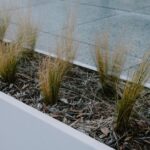 Een stijlvolle grote stalen plantenbak in een moderne tuin met bloemen en groen.